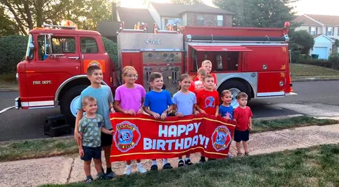 Kids holding a Fantastic Fire Dept Happy Birthday banner in front of the fire truck